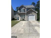 Charming two-story home with a one-car garage and a spacious concrete driveway with a well-manicured lawn at 2317 Hackamore Dr, Atlanta, GA 30349