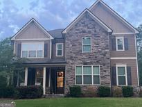 Charming two-story home with stone and wood siding and inviting front porch with chairs at 8340 Nolandwood Ln, Villa Rica, GA 30180