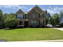 Beautiful two-story home with a stone facade, manicured lawn, and driveway at 8340 Nolandwood Ln, Villa Rica, GA 30180