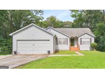 Charming home featuring a two-car garage and a well-maintained lawn, surrounded by mature trees at 160 Country Mill Ln, Stockbridge, GA 30281