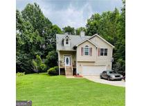 Charming two-story home with a well-manicured lawn and attached garage, nestled among lush trees at 1432 Eagles Nest Cir, Carrollton, GA 30116