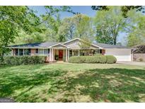 Charming single-story brick home with a well-manicured front yard and a vibrant red front door at 1448 Diamond Head Cir, Decatur, GA 30033