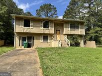 Charming two-story home with a front yard and driveway, surrounded by mature trees on a partly cloudy day at 4079 Day S Trl, Ellenwood, GA 30294