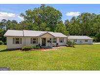 Charming single-story home featuring a metal roof, neutral siding, well-manicured lawn, and detached garage at 204 First St, Bowdon, GA 30108