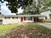 Charming single-story white brick home with a bright red front door and a covered carport at 3730 Stephanie Sw Dr, Atlanta, GA 30331