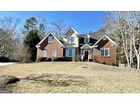 Charming brick home with a well-manicured lawn and a classic architectural design, under a clear blue sky at 1920 Lee Patrick Dr, Dacula, GA 30019
