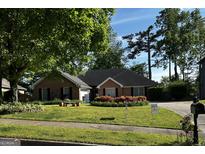 Well-maintained brick home with a lush lawn, mature trees, and vibrant flower beds adding curb appeal at 187 Pine Branch Dr, Stockbridge, GA 30281