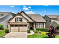 Charming home with a two-car garage, stone accents, and well-manicured landscaping on a sunny day at 123 Mulberry Ct, Peachtree City, GA 30269