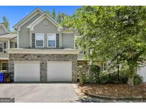 Charming townhome featuring a two-car garage with stone accents, mature landscaping, and neutral siding at 508 Las Brasis Ct, Peachtree City, GA 30269