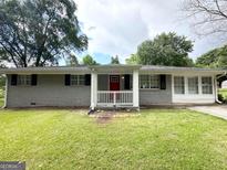 Charming single-story home with a brick facade, a red front door and a well-maintained lawn at 3948 Regent St, Douglasville, GA 30134
