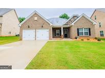 Charming brick home features a two-car garage, well-maintained lawn, and inviting front entrance at 1243 Polk Xing, Mcdonough, GA 30252