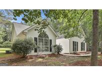 Charming single-Gathering home boasts a striking arched window and black shutters, nestled amongst mature trees at 288 Winthrop Dr, Sharpsburg, GA 30277