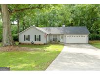 Charming single-story home featuring a well-manicured lawn, gray siding, and a welcoming front porch at 312 Iron Horse Way, Stockbridge, GA 30281