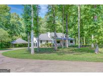 Charming home exterior with a porte-cochere and driveway, framed by lush trees and landscaping at 1572 Hines Rd, Moreland, GA 30259