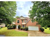 Charming two-story brick home with lush landscaping, a well-manicured lawn, and an attached two-car garage at 759 Hennepin Ter, Mcdonough, GA 30253