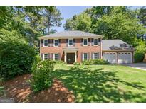 Charming two-story brick home featuring a well-manicured lawn, lush landscaping, and an attached two-car garage at 1850 Linnet Ne Ct, Roswell, GA 30075