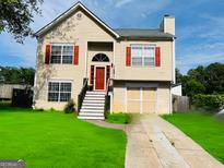 Charming two-story home with red accents, a well-manicured lawn, and a private driveway at 5814 Highgrove Dr, Atlanta, GA 30349