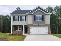 Charming two-story home featuring a brick-accented front, a two-car garage, and a well-manicured lawn at 609 Lobelia Way, Locust Grove, GA 30248