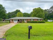 Charming brick ranch home features a well-manicured lawn and mature landscaping at 5141 Hiram Lithia Springs Rd, Powder Springs, GA 30127