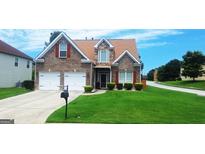 Charming two-story brick home featuring a well-manicured lawn, two-car garage, and classic architectural details at 7314 Basalt Dr, Union City, GA 30291