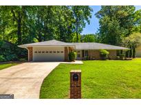 Charming brick ranch home with a well-manicured lawn, a two-car garage and a long driveway at 105 Lake Forest Drive, Peachtree City, GA 30269