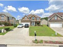 Charming two-story home with a well-maintained lawn and a two-car garage on a sunny day at 718 Florigen Ln, Fairburn, GA 30213
