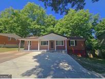 Charming brick home with a covered front porch and a spacious concrete driveway at 1150 Goldsmith Rd, Stone Mountain, GA 30083