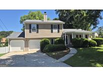 Traditional two-story home with attached garage, landscaped front yard, and welcoming curb appeal on a sunny day at 6120 Raleigh Oaks Ct, Lithonia, GA 30058