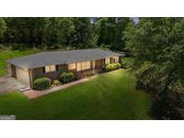 Brick home featuring a lush lawn and mature trees, showcasing its serene setting and classic design at 416 S Carroll Rd, Villa Rica, GA 30180