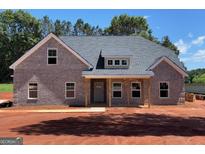 New construction featuring a gray brick exterior, covered front porch and professionally landscaped yard at 1705 Lake Dow Rd, Mcdonough, GA 30252