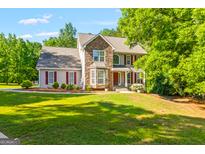 Charming two-story home with stone and vinyl siding, red shutters, a green lawn, and mature landscaping at 220 Drumcliff Ct, Tyrone, GA 30290