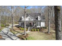 Charming home featuring black shutters and a welcoming front porch nestled among mature trees at 595 S Antioch Rd, Mcdonough, GA 30252