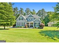 Charming two-story home featuring a well-manicured lawn, lush landscaping, and inviting front porch at 130 Edgewater Trl, Fayetteville, GA 30215