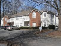 Exterior view of the townhome with parking, covered porches, and a combination of brick and vinyl siding at 4000 Orchard Hill Ter, Stone Mountain, GA 30083
