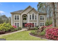 Stucco home featuring professionally landscaped yard with mature trees, colorful azaleas and manicured lawn at 1000 Pleasance Grv, Peachtree City, GA 30269
