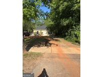 Cozy single-story home with yellow siding, set amongst mature trees and a brick-paved driveway at 908 Emory St, Oxford, GA 30054