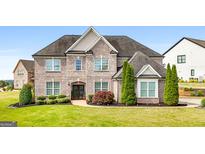Stunning brick home with a meticulously manicured lawn and lush landscaping, exudes curb appeal and timeless elegance at 1516 Winward Dr, Locust Grove, GA 30248