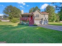 Charming two-story home with a red front door, inviting porch, and well-maintained lawn and mature trees at 2006 Carrollton Hwy, Temple, GA 30179