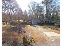 Charming single-story home with a welcoming front yard and a long driveway leading to a covered carport at 4884 Maurice Nw Dr, Lilburn, GA 30047