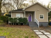 Charming single-story home featuring tan siding, a purple front door, and a cozy front porch with green hedges at 2134 Main Nw St, Atlanta, GA 30318