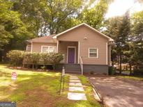 Charming home with a lovely front yard and unique purple front door, surrounded by lush greenery at 2134 Main Nw St, Atlanta, GA 30318
