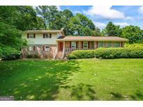 Charming two-story home with brick facade, red shutters, and well-maintained landscaping in a lush, green setting at 7121 Forest Se Dr, Covington, GA 30014