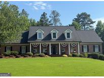 Charming brick home featuring dormer windows, classic shutters, and a well-manicured front lawn at 704 Branchview Ct, Mcdonough, GA 30252
