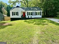 Charming home featuring a red front door, black shutters and a well-manicured lawn at 1681 Stanton Sw Rd, Atlanta, GA 30311
