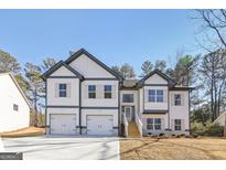 Charming two-story home featuring a two-car garage, stone accents, and a welcoming entrance with wooden steps at 3278 Greenhill Dr, Villa Rica, GA 30180