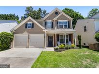 Charming two-story home with a two car garage, beautiful lawn, and a cozy front porch at 169 Wallnut Hall Cir, Woodstock, GA 30189