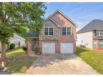 Charming two-story brick home featuring a well-manicured lawn, two-car garage, and stone accents at 11657 Flemming Ct, Hampton, GA 30228