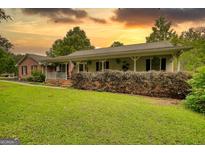 Charming single-story home with a welcoming front porch, lush lawn, and brick facade at 78 N Pomona Rd, Hampton, GA 30228