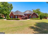 Charming red brick home features a manicured lawn, mature trees, and a welcoming front entrance at 125 Lake Park Dr, Sharpsburg, GA 30277