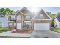 Two-story brick home featuring a well-manicured front yard and an attached two-car garage at 365 Othello Dr, Hampton, GA 30228